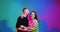 Cool young joyful romantic couple or friends girl and boy embracing in colourful neon studio light. Union concept