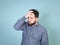 Cool and young man with black hair and black beard posing in front of blue background doing different body exprssions