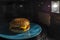 Cooled, appetizing cheeseburger with a sesame bun, meat and cheese in a blue plate was set to warm up in a microwave