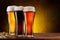 Cooled glasses of  three different beer on the wooden table. Dark brown background