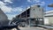 The cooling tower is located in a large data center building installed on the roof on a bright blue sky. And there are white