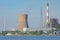 Cooling tower surrounded by windmills, electricity pylon and chimney trees in the harbour of Ghent