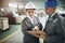 Coordinating shipping on the factory floor. two managers in workwear talking together over a clipboard while standing on