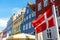 Copenhagen iconic view. Denmark flag against Nyhavn canal with colorful medieval houses in the center of Copenhagen, Denmark