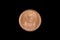 A copper colored South African coin shot on a black background