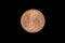 A copper colored South African coin shot on a black background