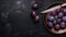 A copper dish with ripe prunes in water drops and a fruit knife on a dark slate background