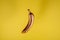 Copper gold floating banana on yellow background. Minimal food concept