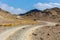 Copper Hike trail, winding gravel dirt road through Wadi Ghargur riverbed and rocky limestone Hajar Mountains in Hatta, UAE