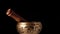 Copper singing bowl rotates around its axis on a black background. Tibetan musical instrument for meditation and alternative medic