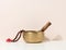 Copper singing bowl and wooden clapper on a white table. Musical instrument for meditation, relaxation, various medical practices