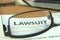 Copy of a lawsuit behind glasses on a desk, 3D rendering