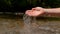 COPY SPACE: Youthful woman pours the cold glassy water back into mountain stream