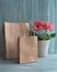 Coral gerbera daisy flowers and craft papper shopping bags on rustic background, copy-space