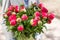 Coral peonies in a glass vase. The woman holds in her hands. Beautiful fresh cut bouquet, the work of the florist at a