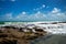 Coral reef at the edge of the sea bathed in sea foam. Small waterfalls of rocks below the horizon