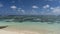 Corals are visible through the clear turquoise water of the ocean.