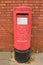 Corby, U.K., June 20, 2019 - traditional british red postbox near brick wall