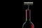 Corckscrew in bottle of red wine on black background