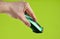 Cordless clipper in a male hand isolated on a green background.