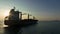 corgo ship container in silhouette and over the sunlight at evening in open sea. aerial view