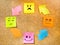 Cork board with colorful post its representing various emoticons with various emotions communication concept