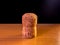 Cork plug from champagne or sparkling wine stands on a wooden surface with black background and a hint of lighting from the upper