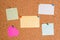 Corkboard with different color and size papers fixed by a pin. Rectangle and square shaped sheets stuck on a billboard