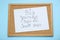 Corkboard with pinned message Big Journeys Begin With Small Steps on light blue background, top view. Motivational quote