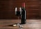 Corkscrew, glass and bottle of red wine on wooden table