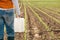 Corn crop protection concept, female farmer agronomist holding jerry can container canister with pesticide