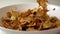 Corn flakes, dried fruits and raisin scatter on white plate super slow motion