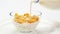 Corn flakes in a glass bowl pouring with milk