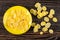 Corn flakes in saucer, scattered cornflakes on wooden table. Top view