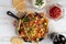 Corn nachos topped with ground beef, melted cheese, vegetables, and guacamole in a cast iron skillet