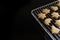 Corner of a baking grid with freshly baked gingerbread cookies for Christmas on a black background with large copy space