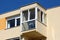 Corner balcony with large glass surface on top of colorful renovated apartment building