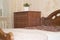 A corner in the bedroom by the window with a plant on the dresser and a bed in brown tones.