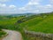 A corner of a country road going downhill surrounded by stones walls and spring meadows in yorkshire dales countryside