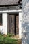 Corner entrance to old abandoned suburban family house in shape of partially open dilapidated wooden doors