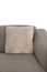 Corner fragment of beige grey upholstered couch with velour decorative cushion on white wall background. Isolated