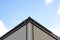 Corner of a house with a plastic brown waterdrop, against a light cloudy sky