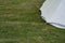 The corner of a large tent attached to the ground on the grass