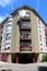 Corner of old renovated apartment building with multiple rounded balconies secured with metal fence and surrounded with stone