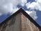 Corner perspective of old brick house with closed wooden shutters. Blue sky with clouds. Caribbean construction Tropical