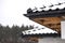 The corner of the roof of a single-family house is covered with snow. Visible the ridge, roof trusses and falling snow.