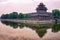 Corner Tower of Forbidden City under the outer Moat at dusk. tower and trees are reflected in the water