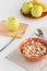 Cornflakes in bowl with fresh apples, bananas, wooden board on white background