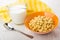 Cornflakes in bowl, jug of milk, yellow napkin and spoon