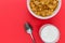 Cornflakes breakfast cereal bowl with milk and spoon on red back